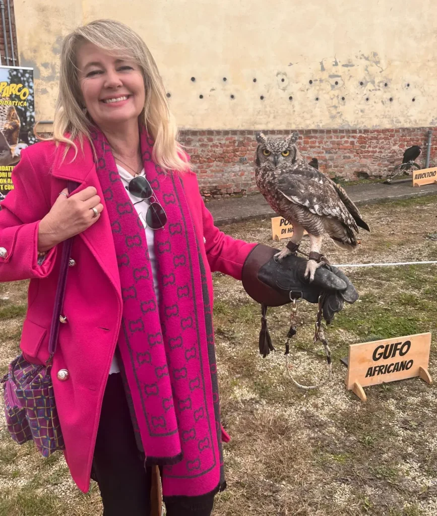 Una visitatrice sorridente con un gufo africano appoggiato sul guantone da falconiere