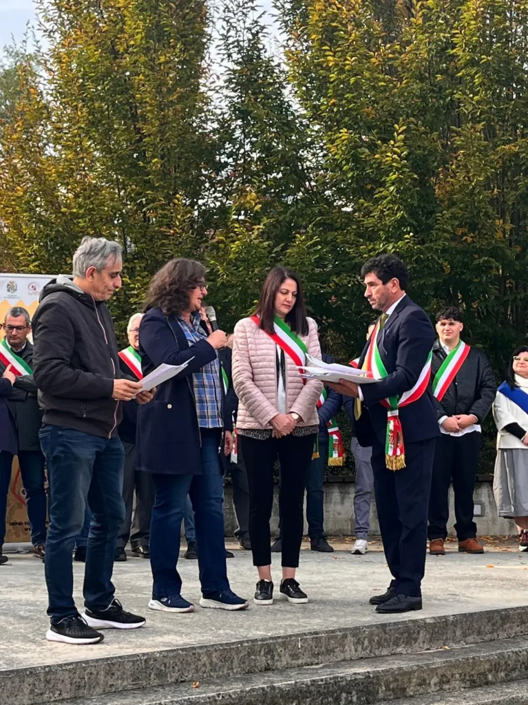 Consegna di un attestato sul palco della fiera tra amministratori con la fascia tricolore