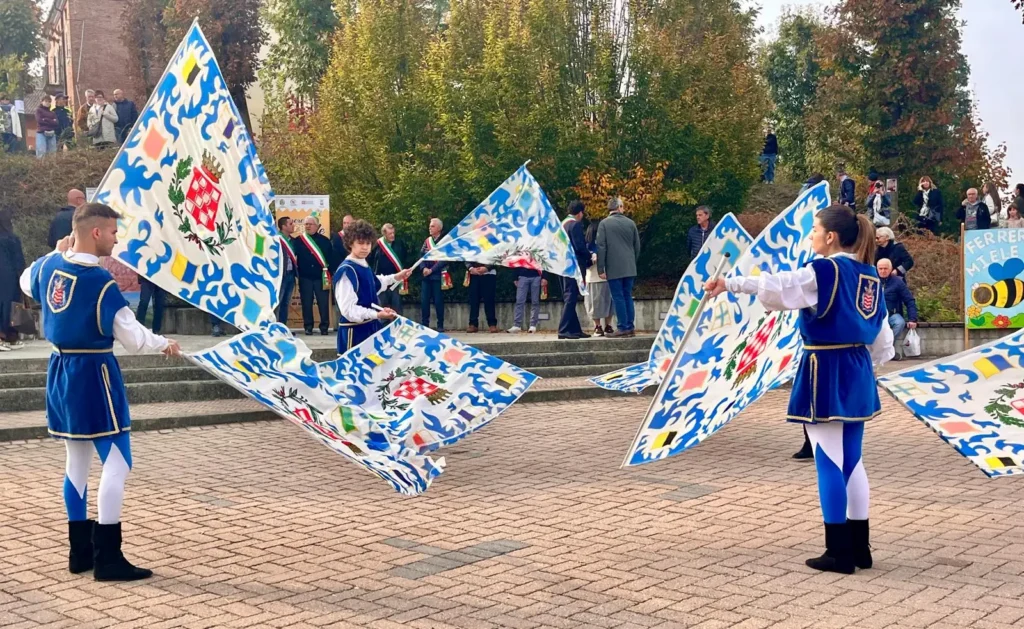 Sbandieratori in costume blu e bianco che fanno volteggiare le bandiere nella piazza