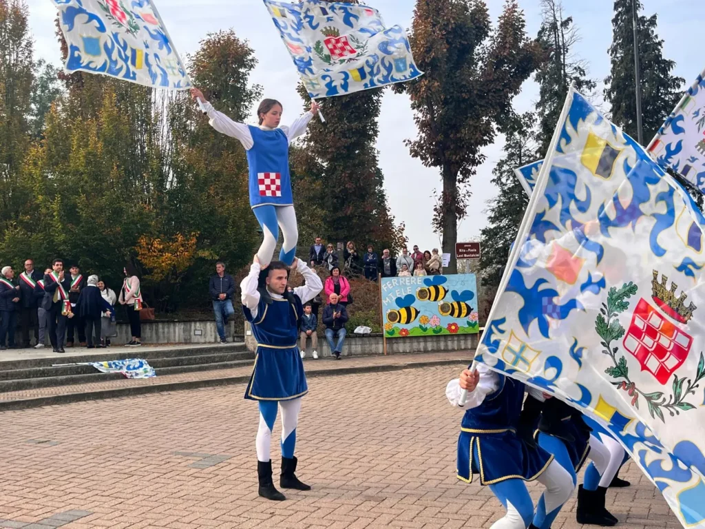 Sbandieratori in costume blu e bianco che fanno volteggiare le bandiere nella piazza