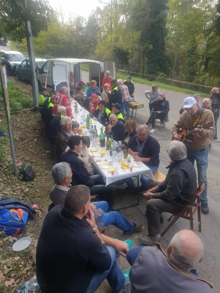 Lunga tavolata all’aperto lungo una strada di campagna, con un chitarrista che suona