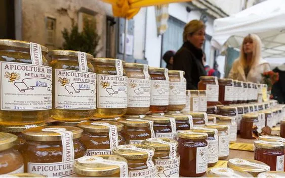 Vasetti di miele di varietà diverse con mestolo che cola miele