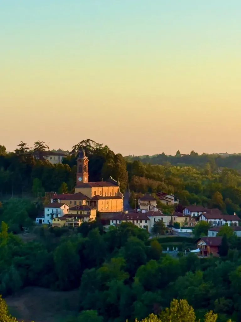 Il paese di Ferrere con il campanile della parrocchiale, visto dalle colline al tramonto