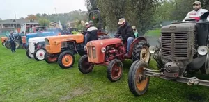 Trattori d'epoca allineati sul prato con i conducenti in sella